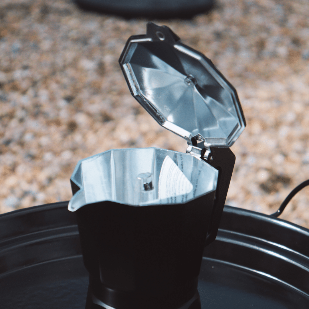 Percolator black, inside. On griddle of outdoor cooking stove
